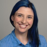 Woman in her 20s with blue hair, smiling